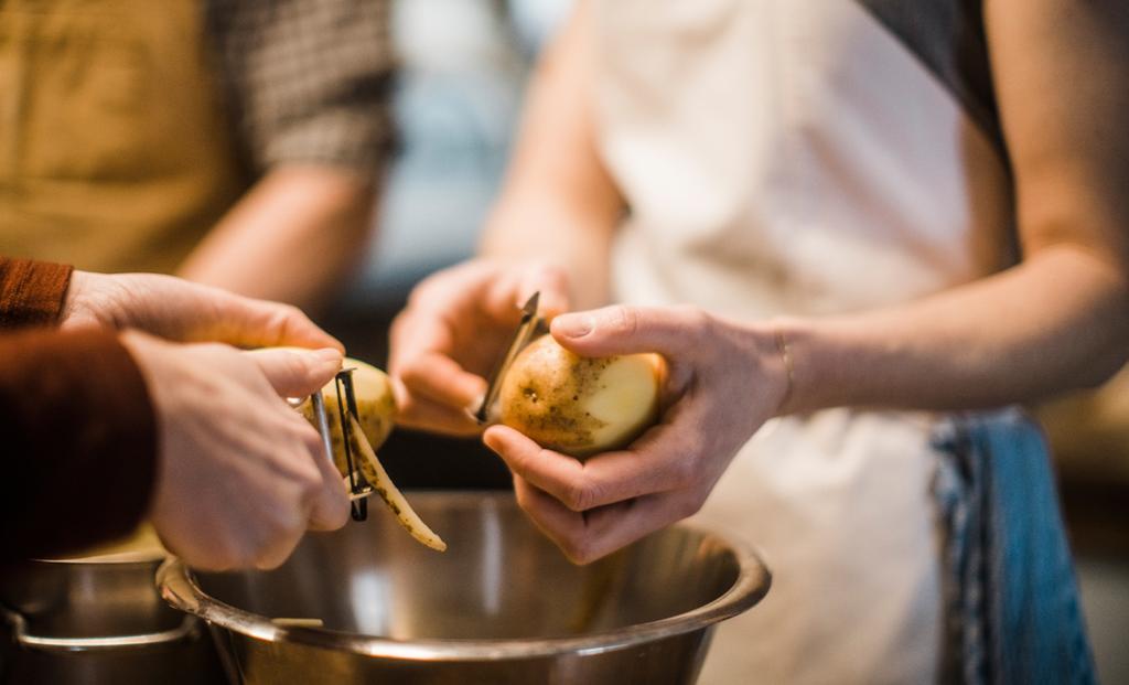 zwei Personen schälen Kartoffeln - Symbolbild